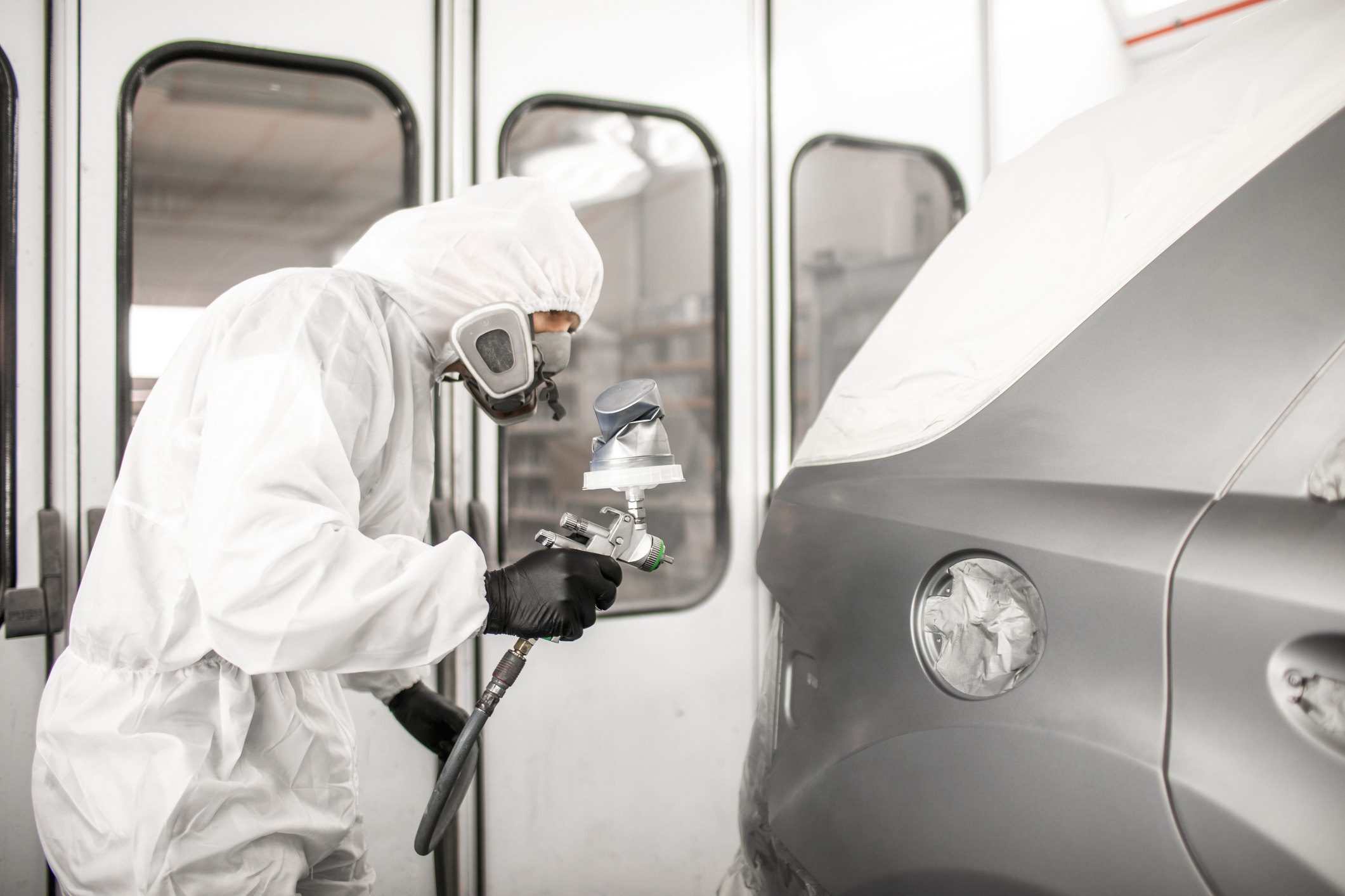 Person spray painting a car in workshop.