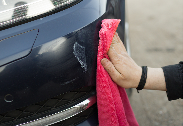 Hand polishing car with red cloth.