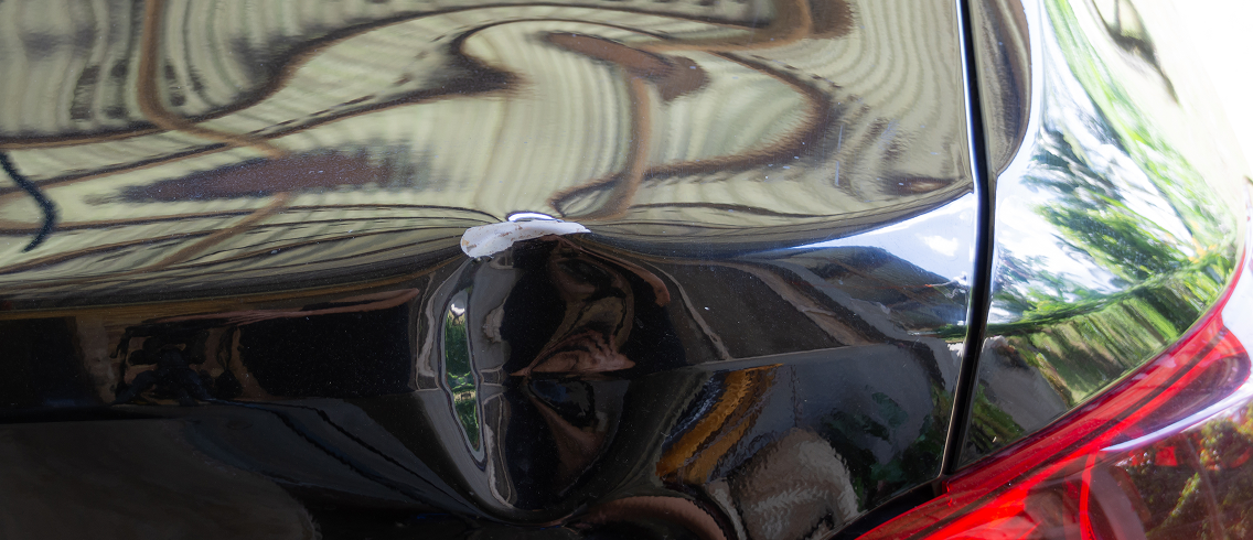 Car with a dent and scratched paint.